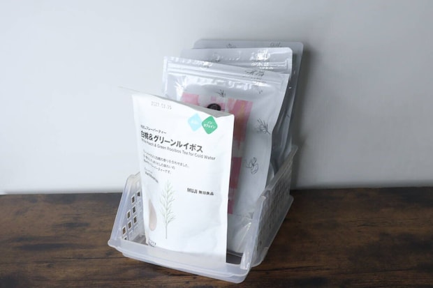 透明な収納ケースに、無印良品のお茶の袋が複数立てて収納されている