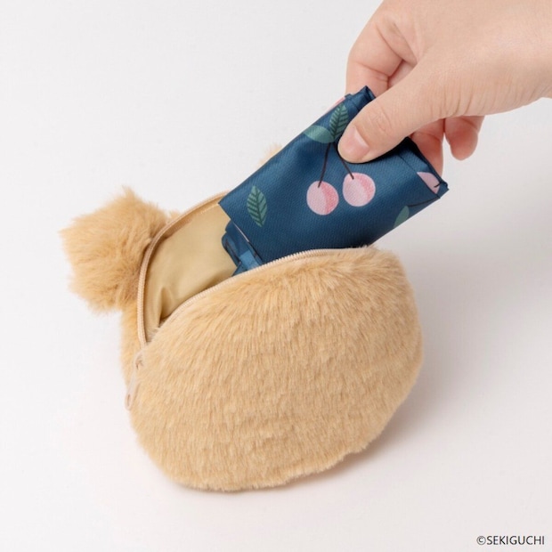 モンチッチのぬいぐるみチャームの中にエコバッグを収納している手元 モンチッチのぬいぐるみチャームの中にエコバッグを収納している手元