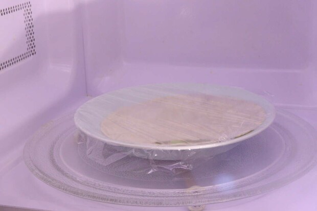 電子レンジの中でラップをかけて温められているトルティーヤ