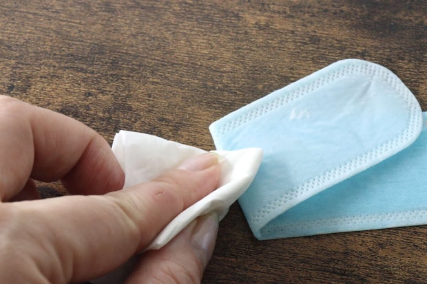 青い液体を吸った汗取りパットの裏側をティッシュで拭いている 青い液体を吸った汗取りパットの裏側をティッシュで拭いている