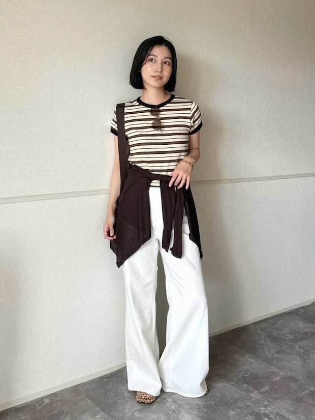 ボーダーTシャツと白いワイドパンツを着用し、腰に茶色いカーディガンを巻いた女性 ボーダーTシャツと白いワイドパンツを着用し、腰に茶色いカーディガンを巻いた女性