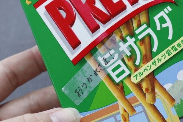 お菓子の箱に半透明シールを貼りメッセージを書いている。 お菓子の箱に半透明シールを貼りメッセージを書いている。