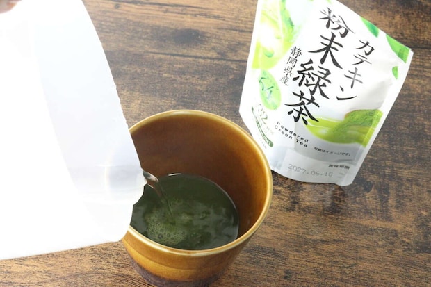 茶碗に入った緑茶の粉末に、白い容器からお湯を注いでいる様子 茶碗に入った緑茶の粉末に、白い容器からお湯を注いでいる様子