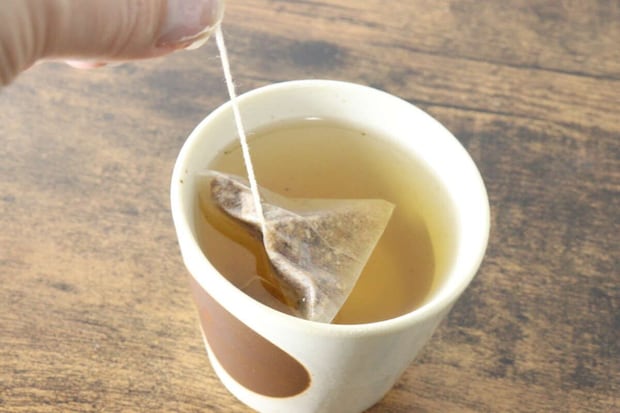茶碗に入ったごぼう茶のティーバッグを指で持ち上げている様子 茶碗に入ったごぼう茶のティーバッグを指で持ち上げている様子