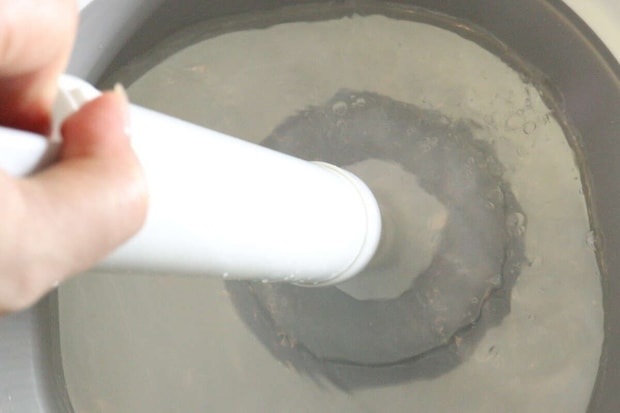 パイプクリーナーを桶の水中で押し引きして吸引力を試している パイプクリーナーを桶の水中で押し引きして吸引力を試している