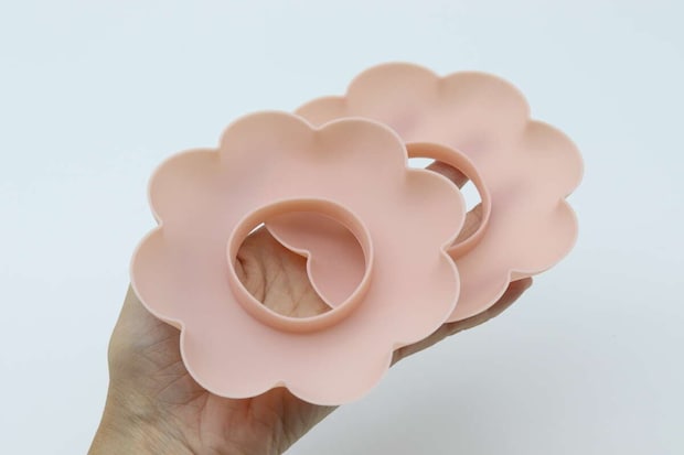 手のひらにピンクの花形洗顔リストバンド2個を重ねて持つ 手のひらにピンクの花形洗顔リストバンド2個を重ねて持つ