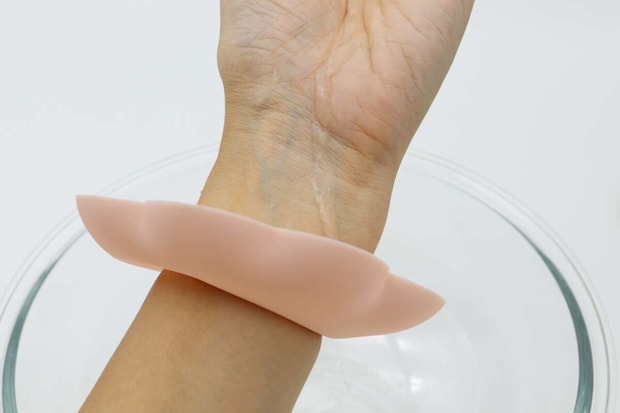 女性の腕に装着したリストバンドと透明な洗面器のアップ