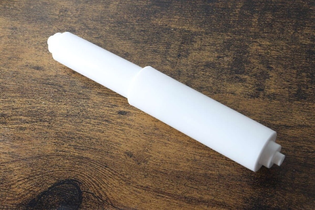 木目調のテーブルに置かれた白いトイレットペーパー替え芯ホルダー 木目調のテーブルに置かれた白いトイレットペーパー替え芯ホルダー