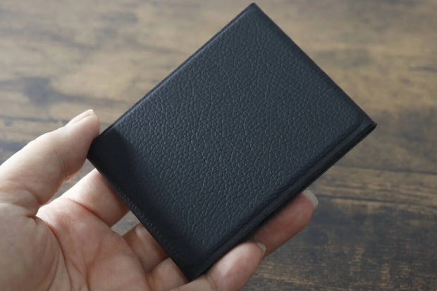 折りたたんだ状態の黒いスマホスタンドを手のひらに乗せている 折りたたんだ状態の黒いスマホスタンドを手のひらに乗せている