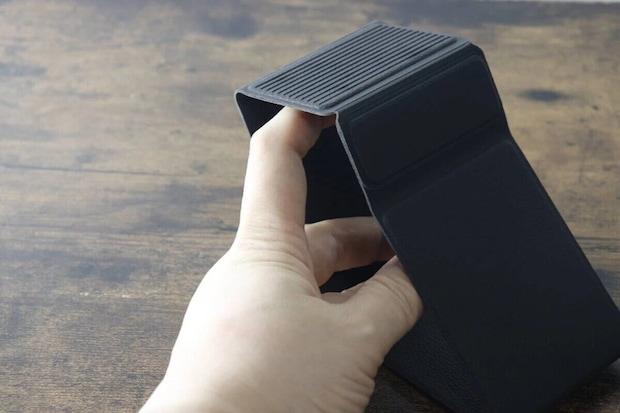 黒い折りたたみスマホスタンドを開いて組み立てている様子 黒い折りたたみスマホスタンドを開いて組み立てている様子