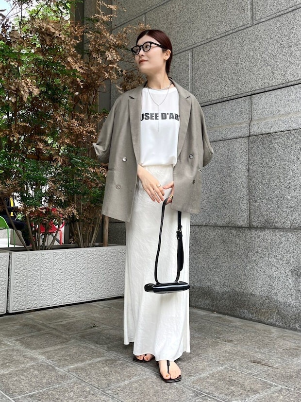 白いロゴTとベージュジャケット、白ナロースカートの女性