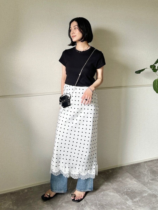黒トップスとドット柄スカート、デニムをレイヤードした女性