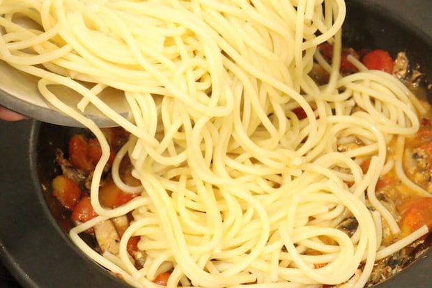 フライパンで煮込まれたソースの中に、茹で上がったパスタが投入され、絡めようとしている様子