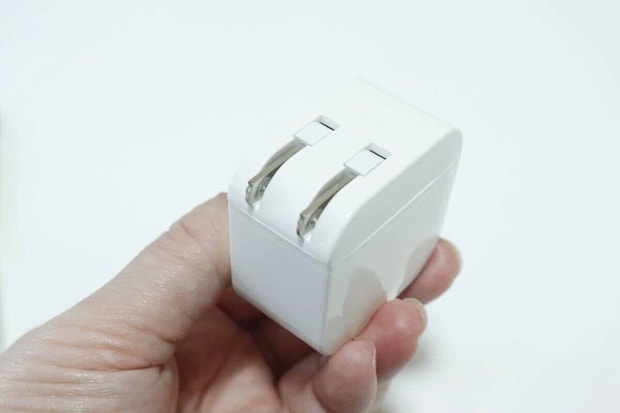 白いUSB充電器のプラグ部分が折りたたまれている様子を手に持っている