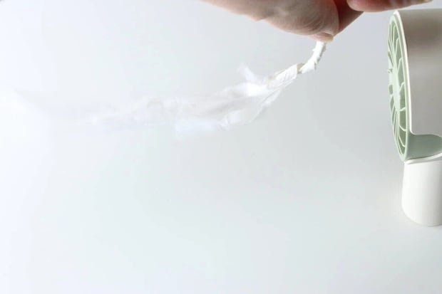 ミニファンの風でティッシュペーパーが勢いよく吹き飛ばされている様子