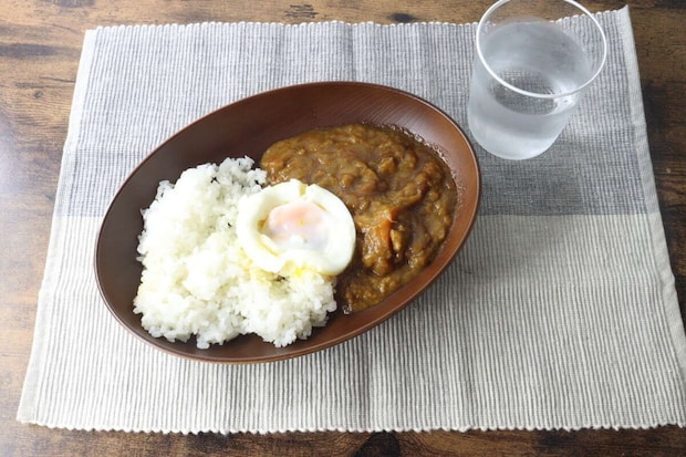 セルビッジランチョンマットの上にカレーライスと水のグラスが置かれた食卓