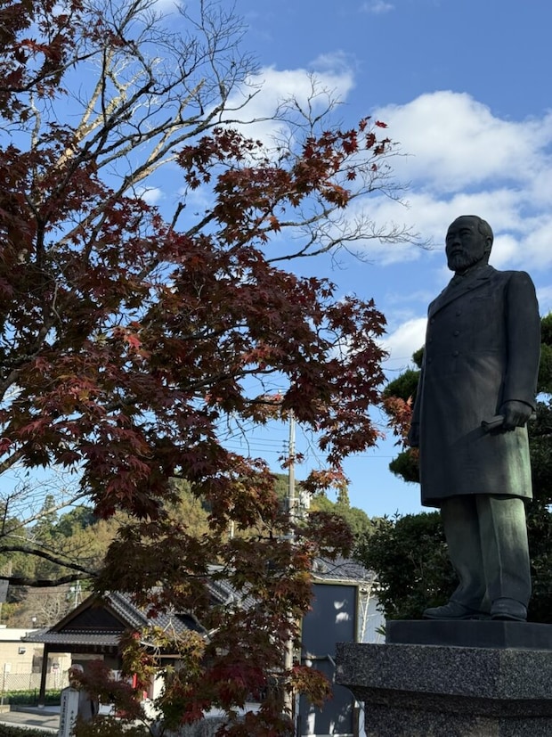 トップ画像。伊藤博文の銅像(立像)とモミジの紅葉の写真。