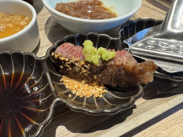 『炭焼食堂 JYUJYUTEI』切り落としステーキ定食の焼いたお肉に薬味をのせた写真。