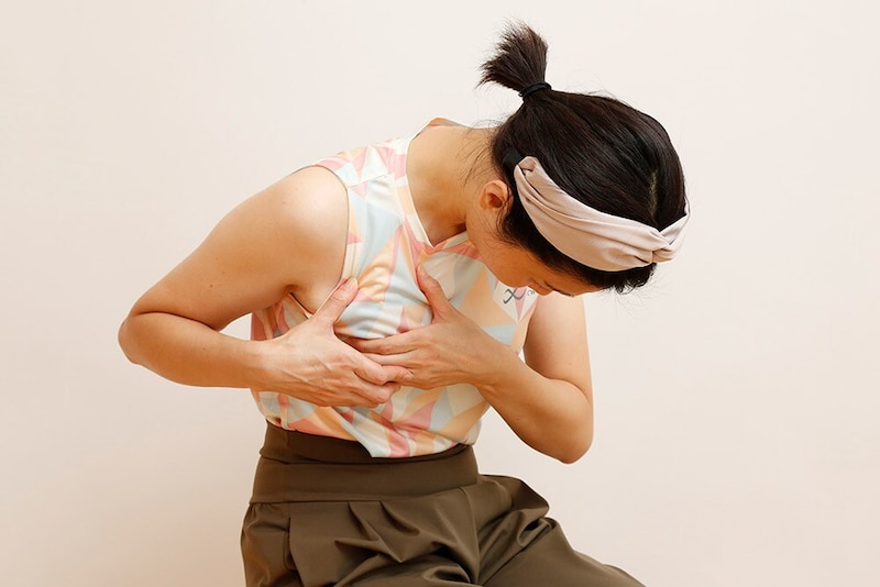 右手も添えて一緒に筋肉をつまみ、下を向き背中を丸めて5回深く呼吸をする。反対側も同様に行う。