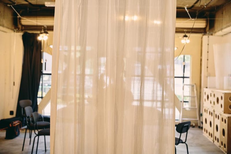 「5005」のカーテン。カーテンの奥で手話で話す牧原さんの影が見える