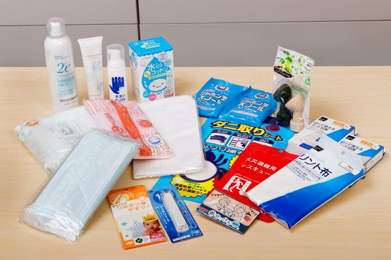 災害時や緊急時にアトピー性皮膚炎患者が必要となる可能性のある、さまざまな備蓄品やケア用品がテーブルの上に広げられた写真。