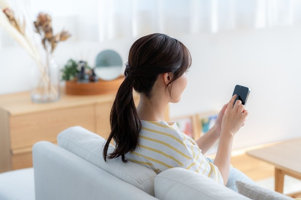 スマホ　後ろ姿　女性　見る　家